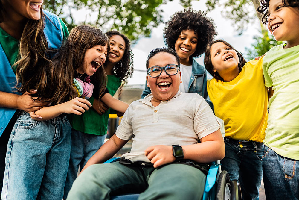Group of kids smiling with a child in a wheelchair